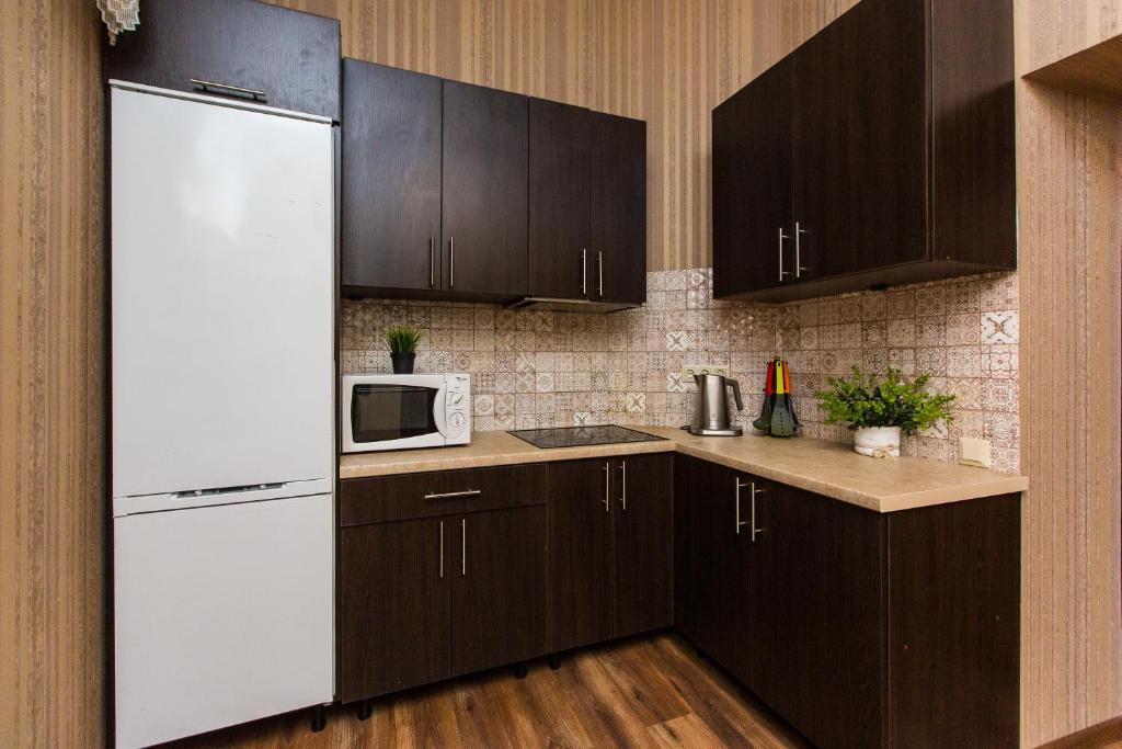 a kitchen with brown cabinets and a white refrigerator at Baker's street in Lviv