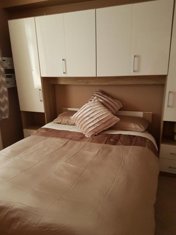 a bedroom with a large bed with white cabinets at Flat by the Sea in Burghead