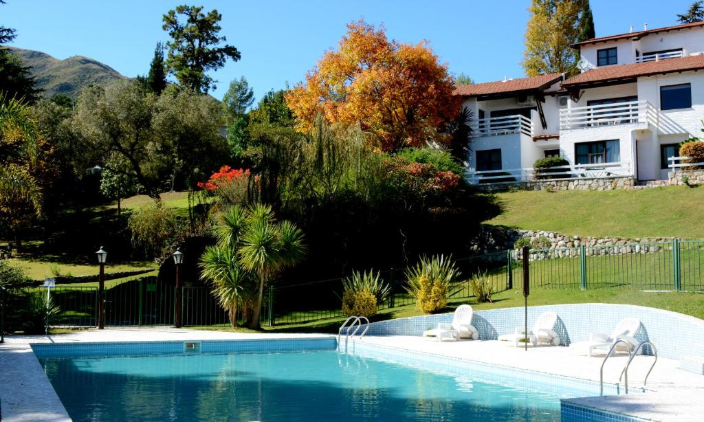 a swimming pool with chairs and a house at Las Ardillas Cabañas y Suites in La Falda