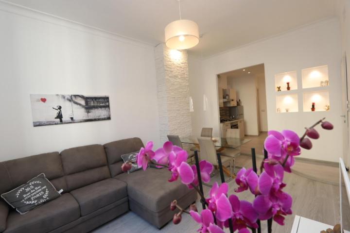 - un salon avec un canapé et des fleurs violettes dans l'établissement Porta Soprana Old Town with FREE PRIVATE PARKING included!, à Gênes
