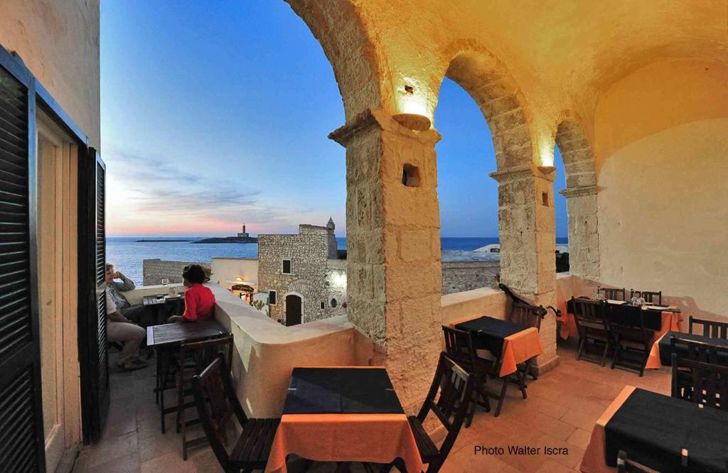 een persoon aan een tafel op een balkon met uitzicht op de oceaan bij Rocca Sul Mare Hotel in Vieste
