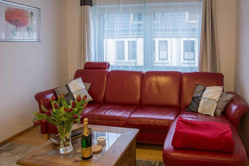 a living room with a red leather couch and a table at Ferienwohnung Rutenberg in Bremerhaven
