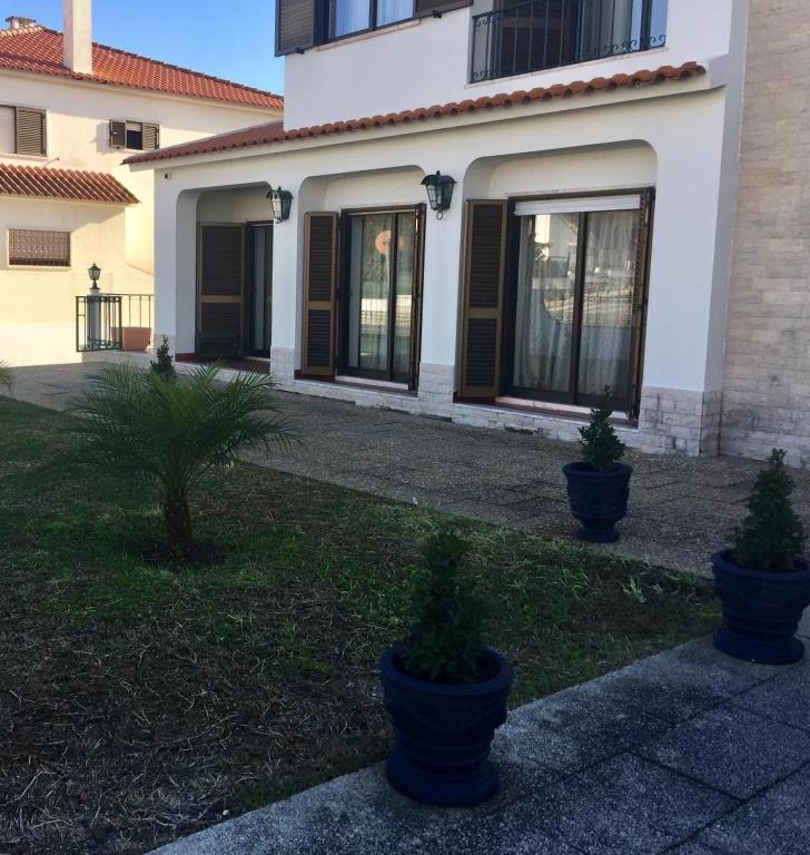 a house with two potted plants in front of it at Paradise Suites in Carcavelos