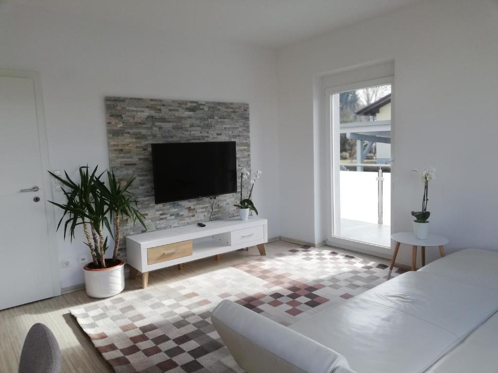una sala de estar blanca con TV en una pared de ladrillo en Gemütliches 3 Zimmer Apartment nahe Graz, en Gratkorn