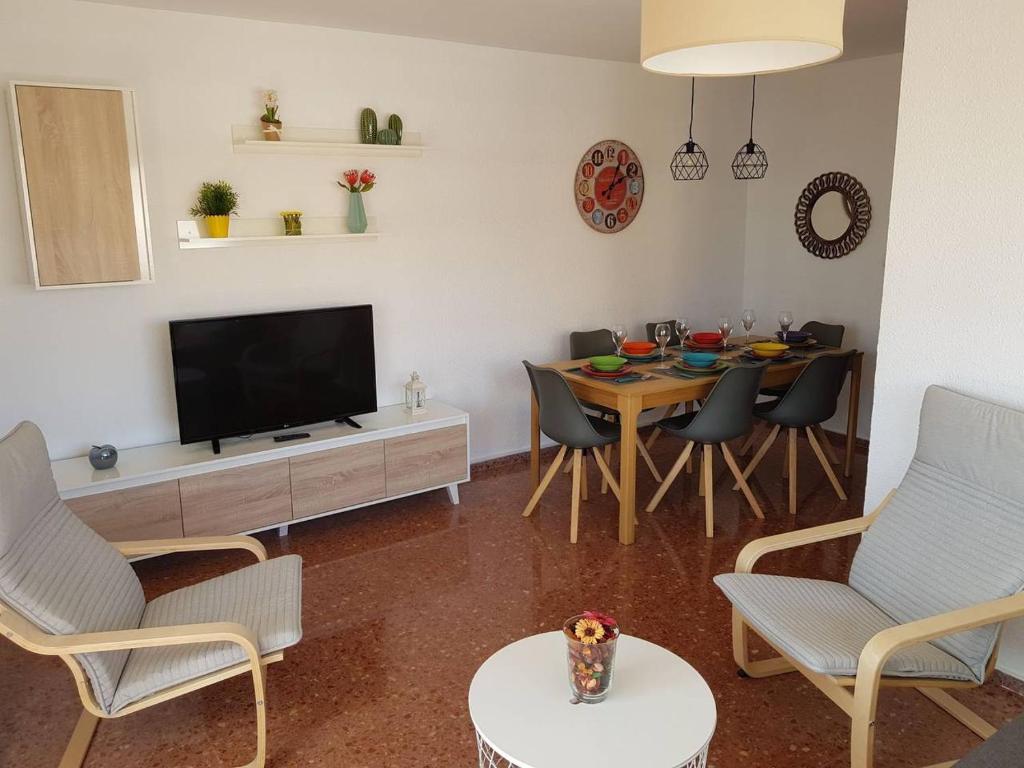 sala de estar con TV y mesa con sillas en Fantástico apartamento cerca de la playa, en Benicàssim