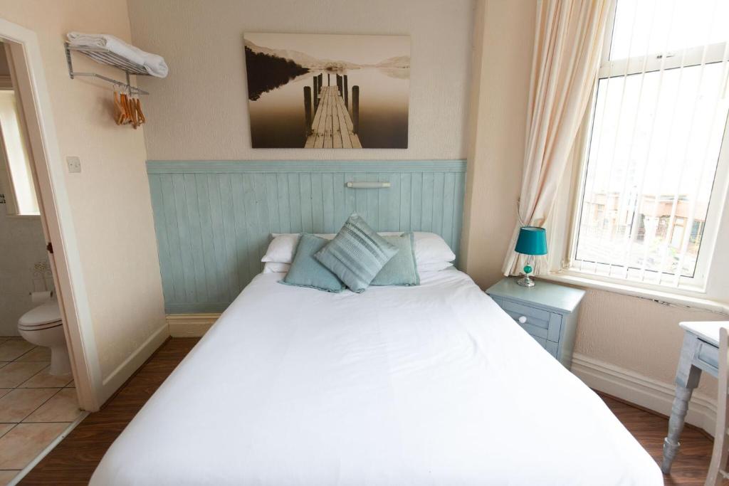a bedroom with a large white bed and two windows at The Osprey Hotel in Blackpool
