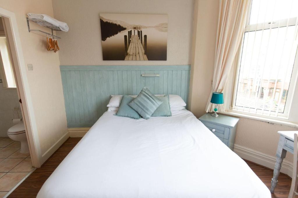 a bedroom with a large white bed and two windows at The Osprey Hotel in Blackpool