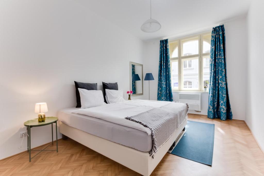 Schlafzimmer mit einem großen Bett und blauen Vorhängen in der Unterkunft JT's Apartments Navrátilova str. in Prag