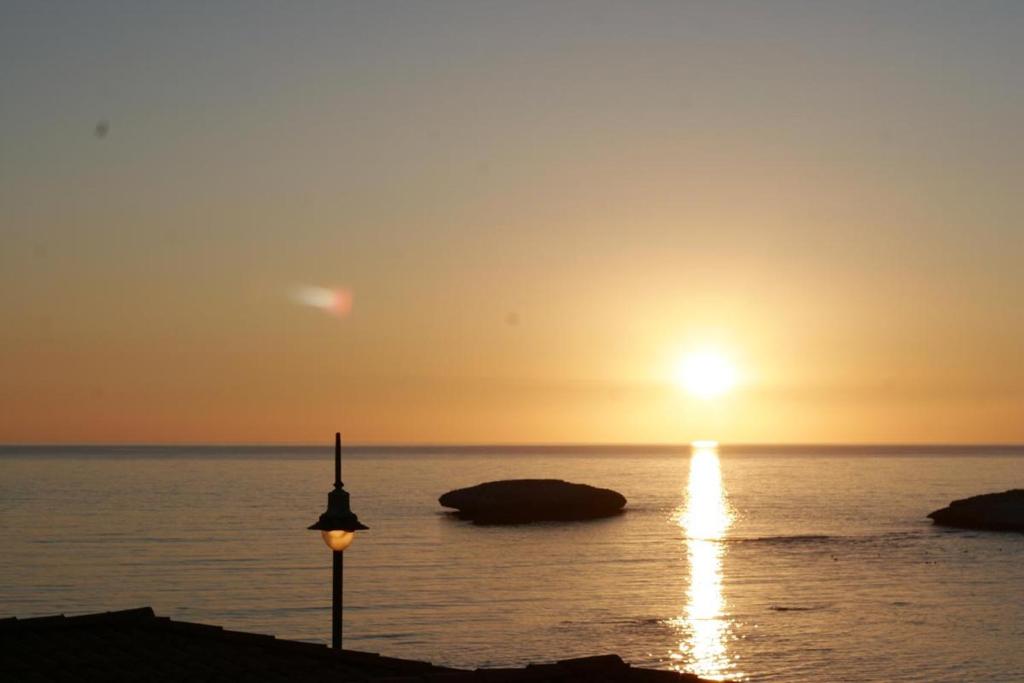 una puesta de sol sobre el océano con una luz de la calle en S'Archittu Bed&Breakfast, en S'Archittu