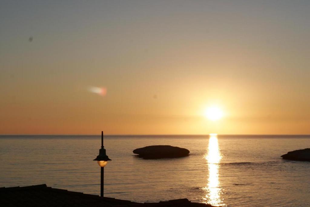 a sunset over the ocean with a street light at S'Archittu Bed&Breakfast in S'archittu Cuglieri