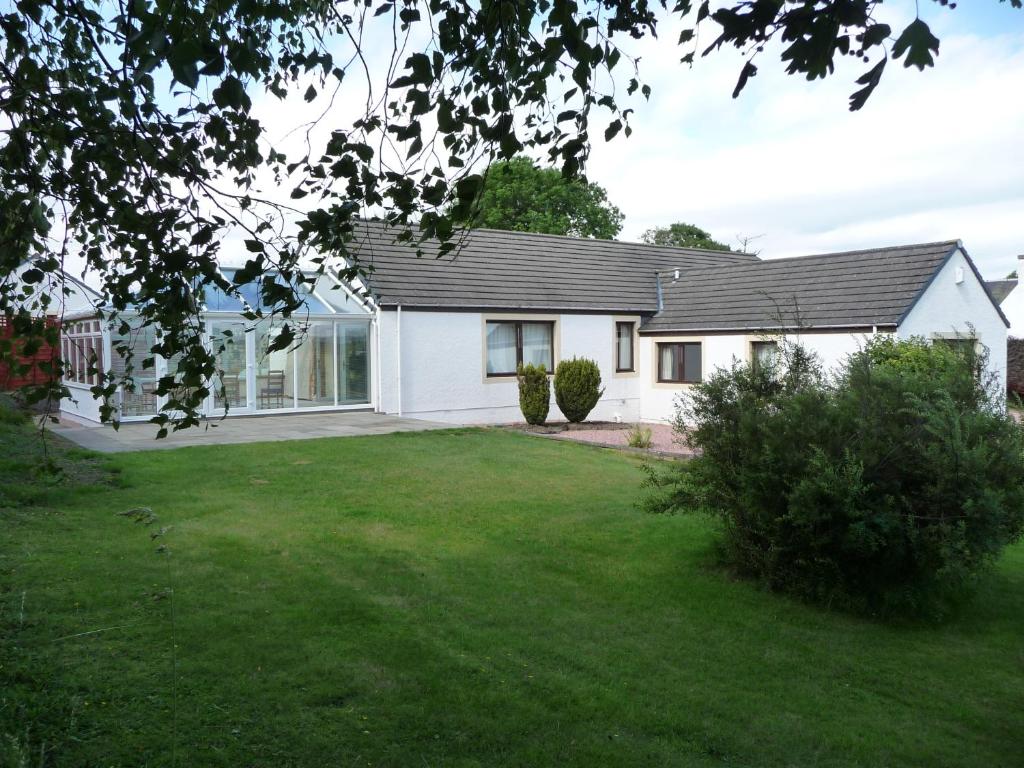 a white house with a black roof and a yard at Ordieview Bed & Breakfast in Luncarty