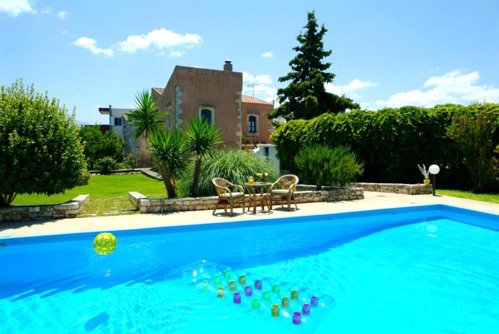 a swimming pool with two chairs and a table in front of a house at PRINOS in Prínos