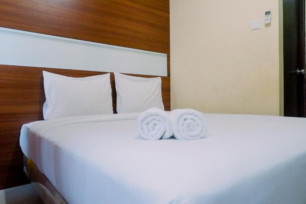 two towels on a bed in a hotel room at Compact Studio Room at Tamansari Papilio Apartment By Travelio in Surabaya