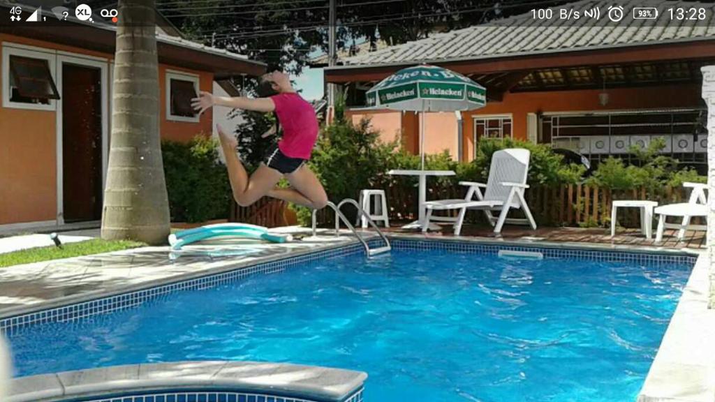 a woman jumping into a swimming pool at Casa Temporada in Jacareí