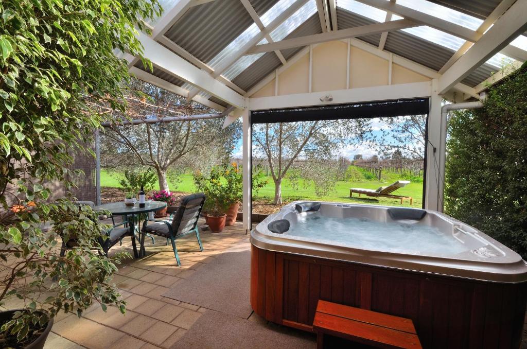 a large hot tub in a patio with a table at Stephanette's Cottage in Lights Pass