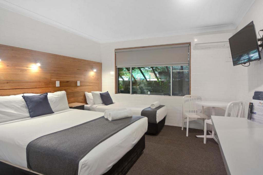 a hotel room with two beds and a table at Pleasant Way River Lodge in Nowra