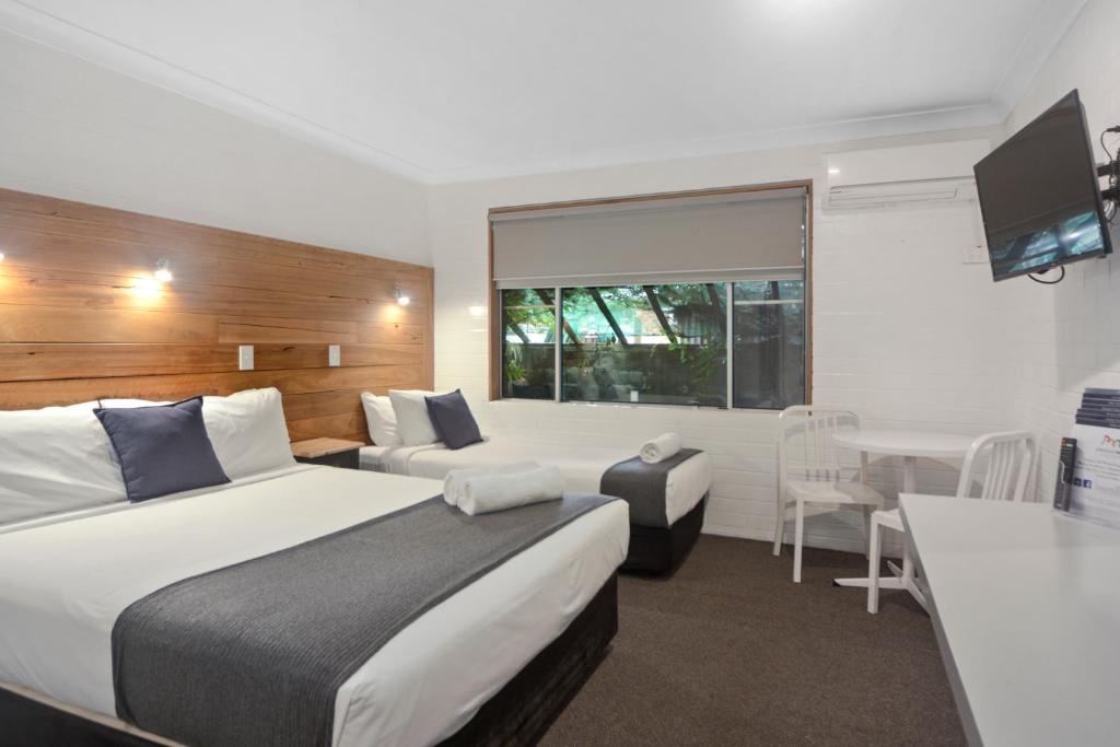 a hotel room with two beds and a television at Pleasant Way River Lodge in Nowra