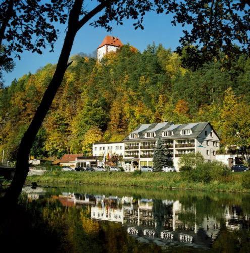 a building sitting on top of a hill next to a lake at Hotel Am Schlossberg in Ziegenrück