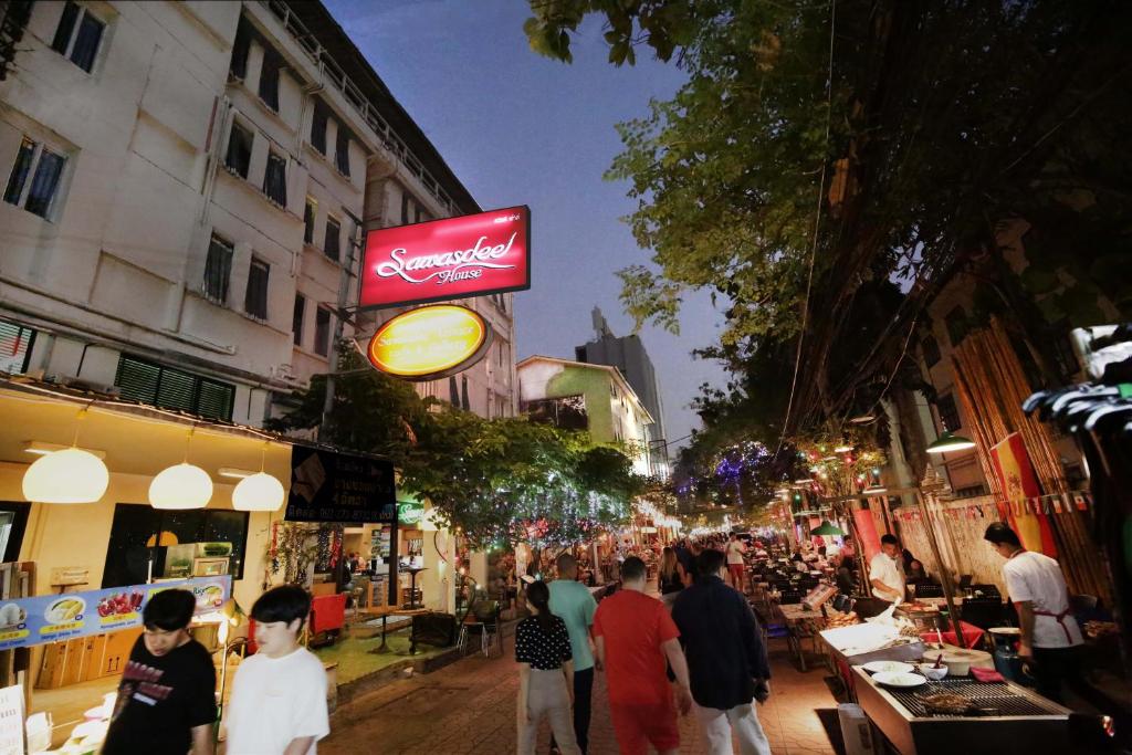 曼谷的住宿－薩瓦斯德酒店，一群人晚上沿着城市街道走