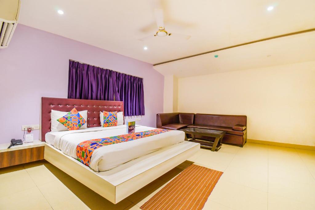 um quarto com uma cama grande e um sofá em FabHotel Pentagon Airport em Bhubaneshwar