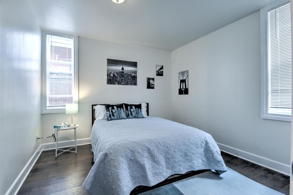 a white bedroom with a bed and two windows at Capitol Hill Luxury Apartments in Seattle