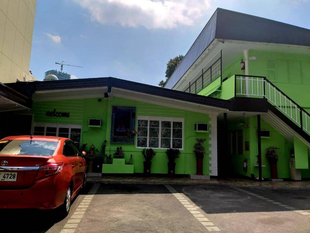 a red car parked in front of a green building at AMBIANZA APARTELLE in Manila