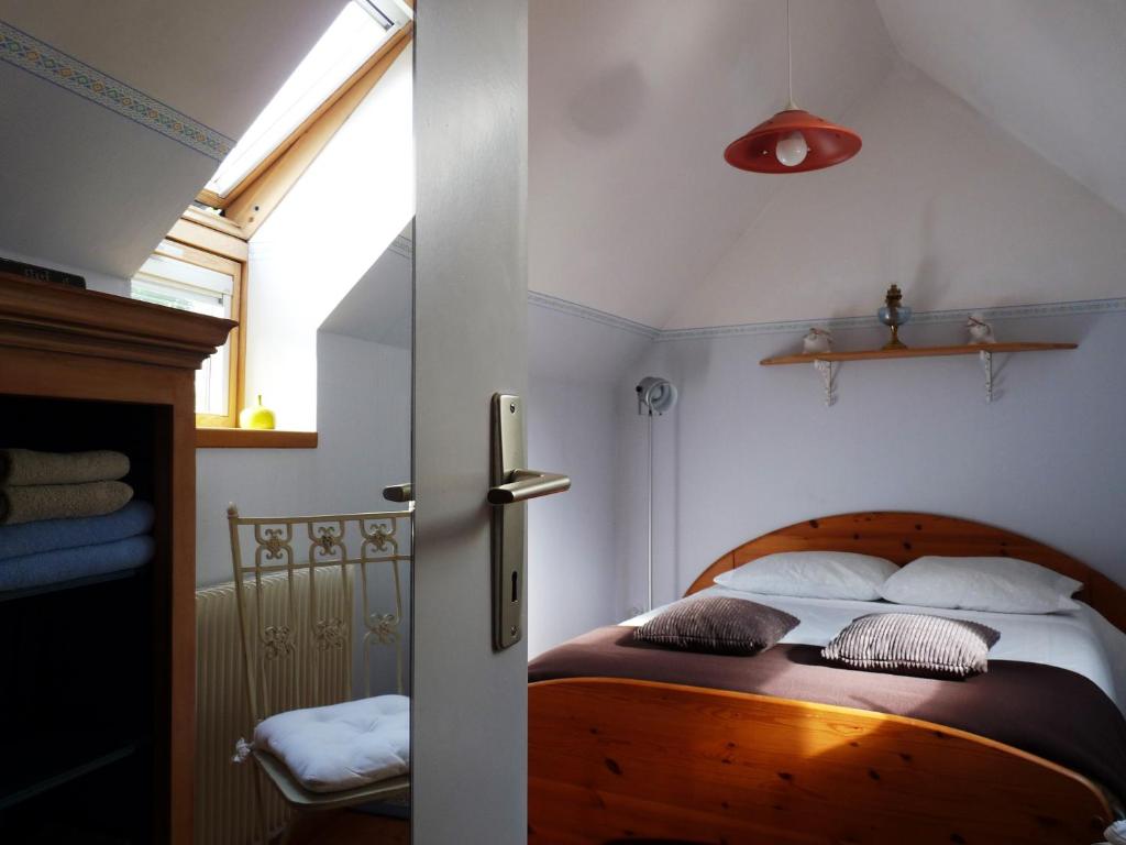 a bedroom with a wooden bed with pillows and a window at Le Petit Grenier in Bayeux