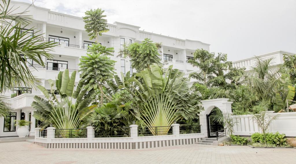 un edificio blanco con plantas delante en Hotel Kangaroo Bujumbura en Buyumbura