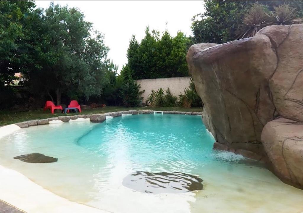 a pool with a large rock in a backyard at Mas Le Colombier in Bompas