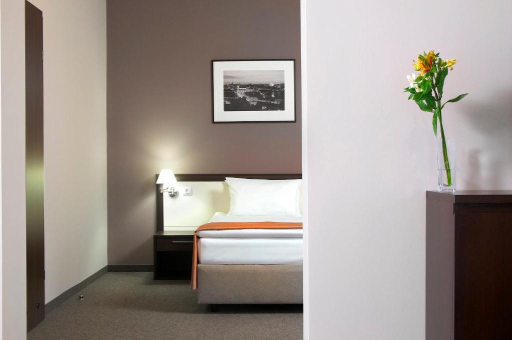 una habitación de hotel con una cama y un jarrón de flores en Lviv Ramada Hotel en Leópolis