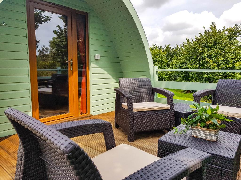 un patio con sillas y mesas en una casa verde en Colemans Cottage Fishery en Wickham Bishops