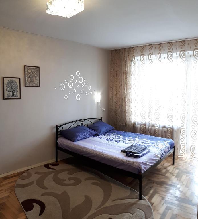 a bedroom with a bed with blue pillows and a window at Апартаменты с панорамным видом на город in Zaporozhye