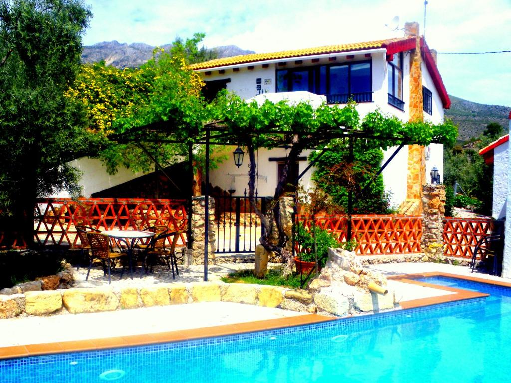 a villa with a swimming pool in front of a house at Alojamiento rural El Agüelo in Huelma