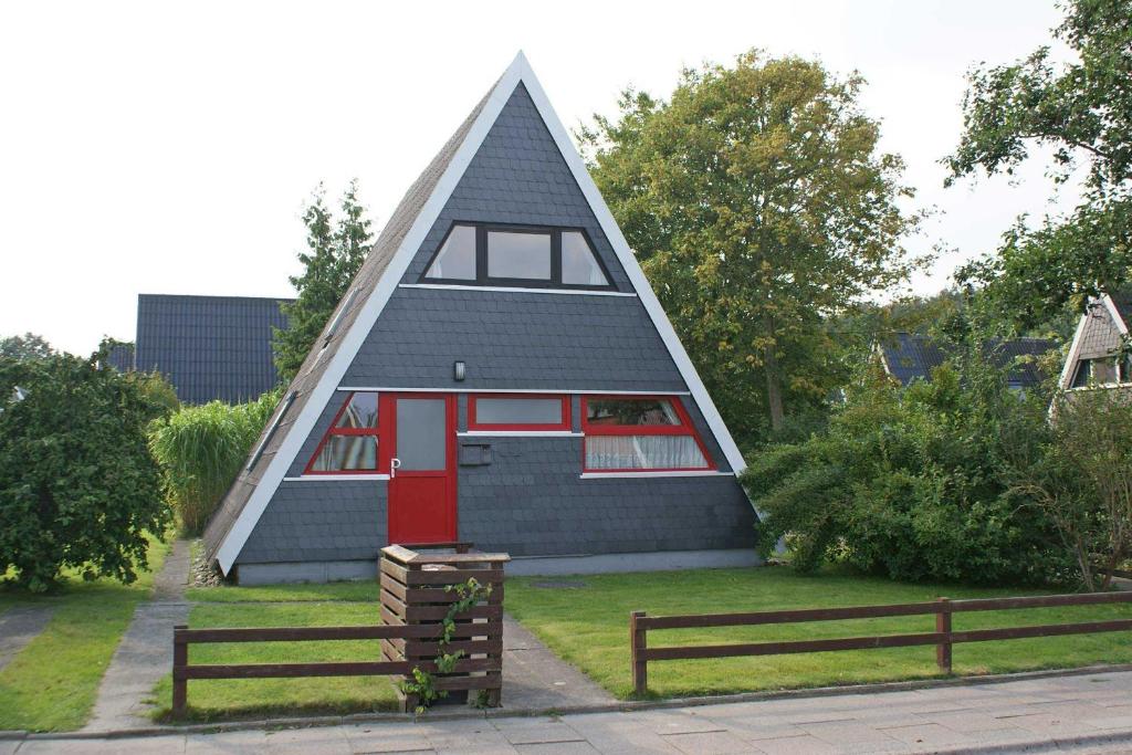 een klein huis met een puntdak en een rode deur bij Zeltdachhaus _ Renovierung 2019 _ in Damp