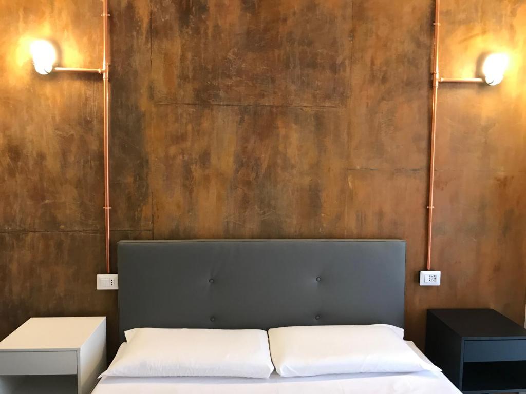 a bedroom with a bed and two lights on the wall at JOY ROOMS in Milan