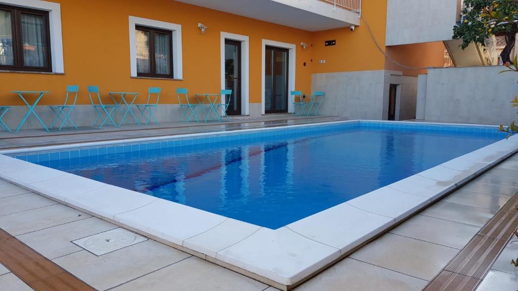 a large swimming pool with blue chairs in front of a building at L'AURORA in Piedimonte Etneo