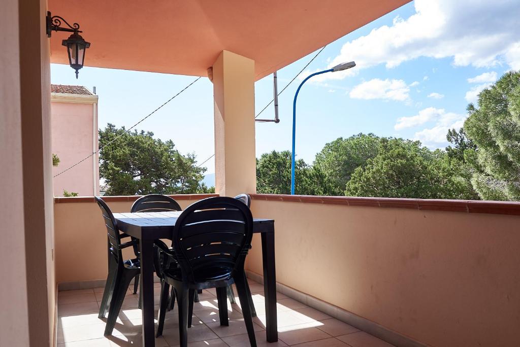 un tavolo e sedie su un balcone con finestra di Appartamento Fresia a Cala Gonone