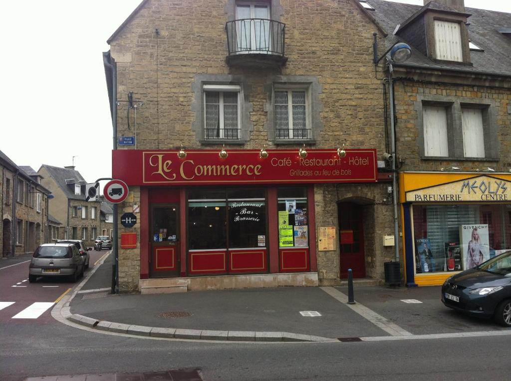 a building with a red storefront on a city street at Le Commerce in La Haye-du-Puits