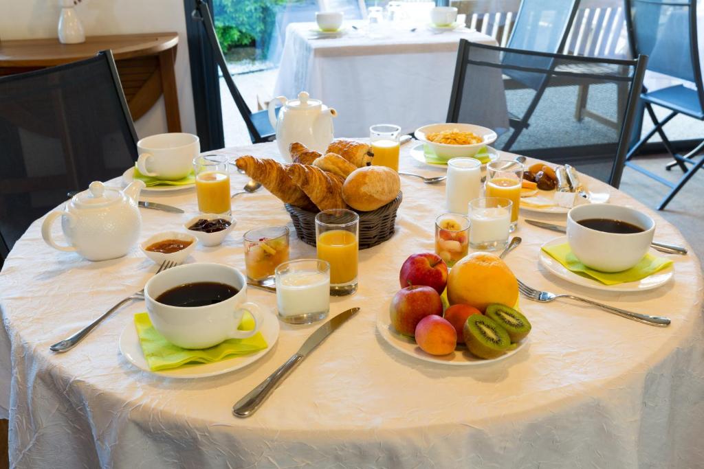 - une table avec des assiettes de produits pour le petit-déjeuner et des tasses de café dans l&#39;établissement Hôtel Les Vignes de la Chapelle, &quot;The Originals Relais&quot;, à Sainte-Marie de Ré