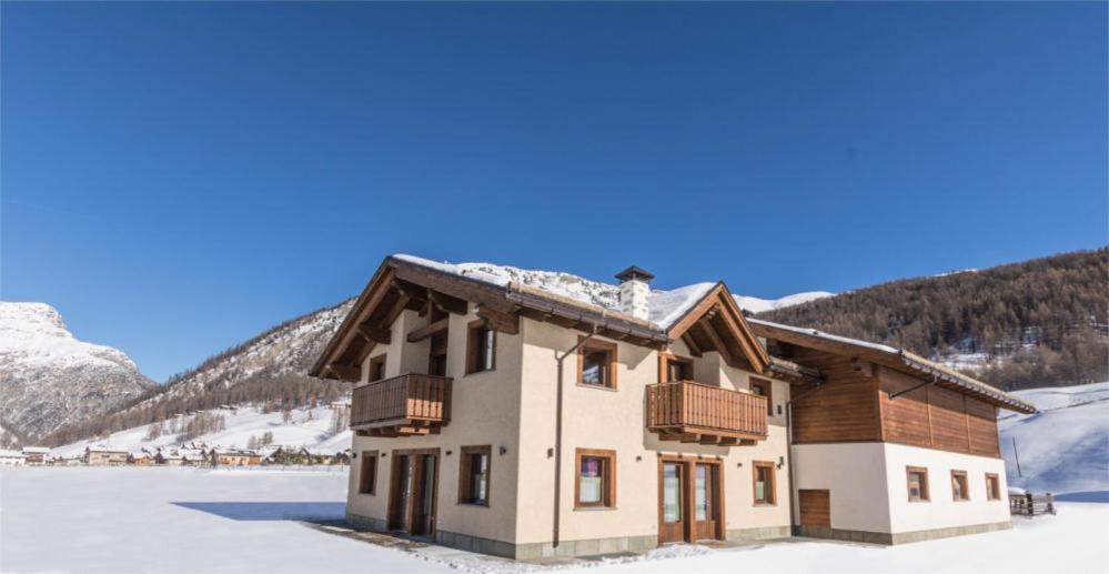 a large white house with a mountain range at Agriturismo La Poina in Livigno