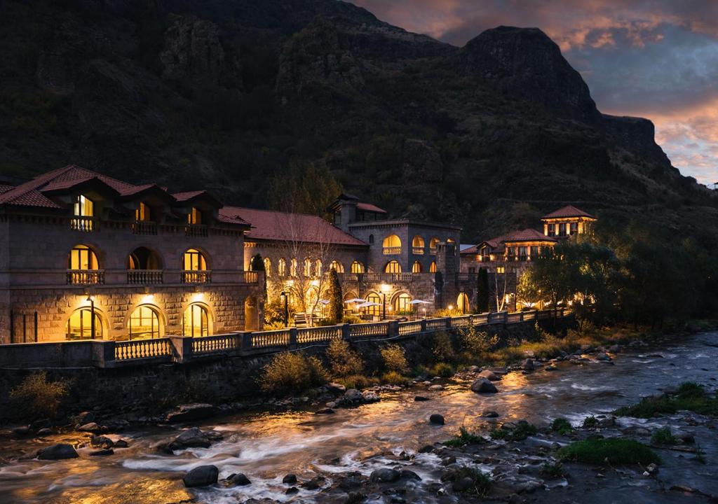 a large building next to a river at night at Tufenkian Avan Dzoraget Hotel in Dzoraget