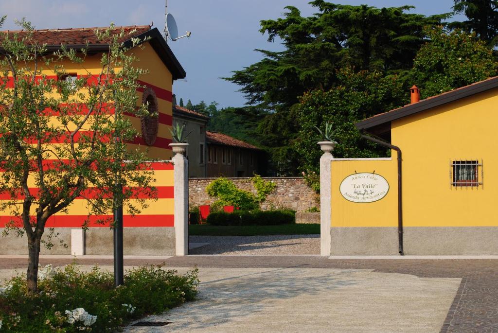 um edifício amarelo e vermelho com uma árvore em frente em Antica Corte la Valle em Sona