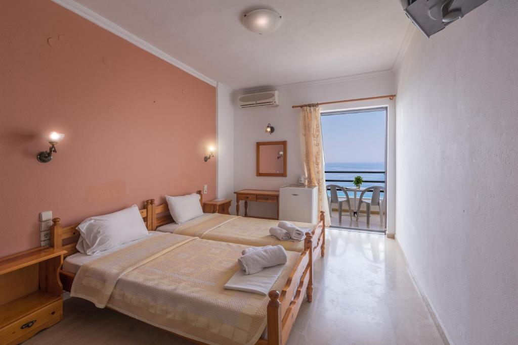 a bedroom with two beds and a view of the ocean at Arilla Beach Hotel in Perdika