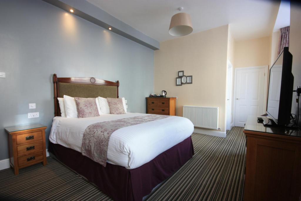 a bedroom with a large bed and a television at The Strathmore in Tenby