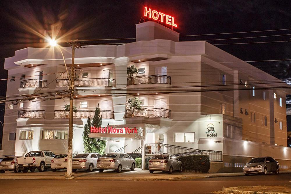 een hotel waar 's nachts auto's voor geparkeerd staan bij Hotel Nova York in Araçatuba