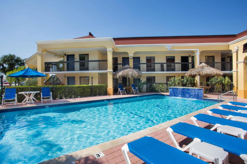 a swimming pool in front of a hotel with chairs and umbrellas at Days Inn by Wyndham Florida City in Florida City