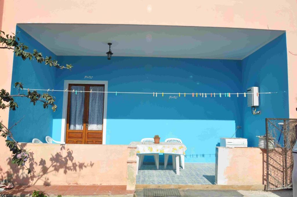 una casa azul con una mesa delante en B&B Il Gabbiano, en SantʼAntìoco