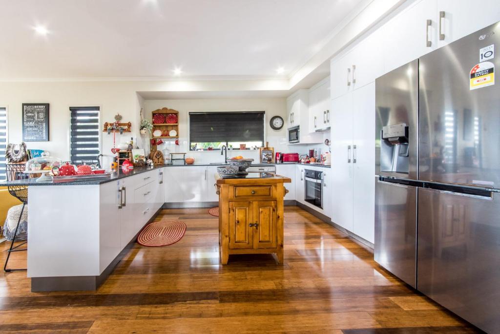 a large kitchen with white cabinets and stainless steel appliances at Austinmer - Cannonvale in Airlie Beach