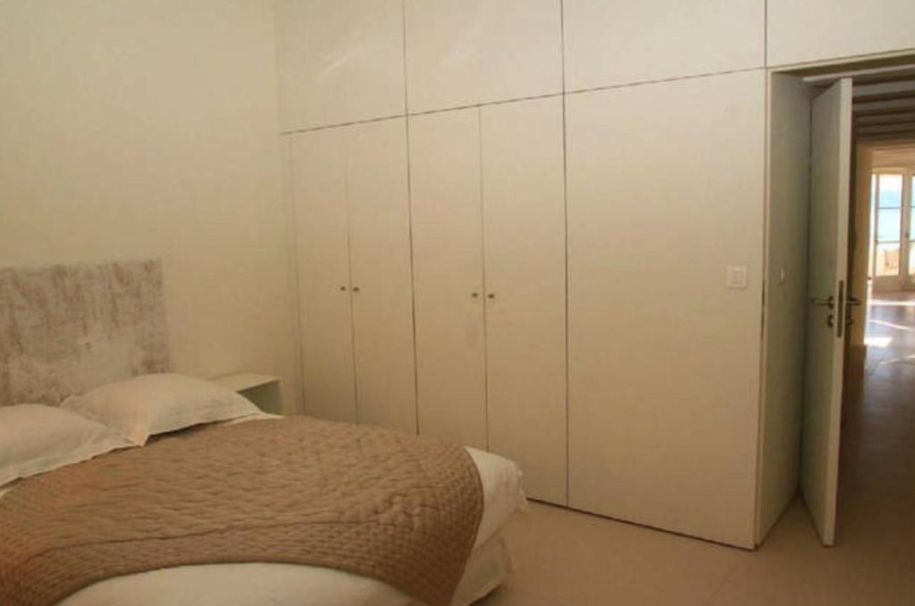 a bedroom with a bed and white cabinets at L’Ile Rousse les pieds dans l’eau in LʼÎle-Rousse