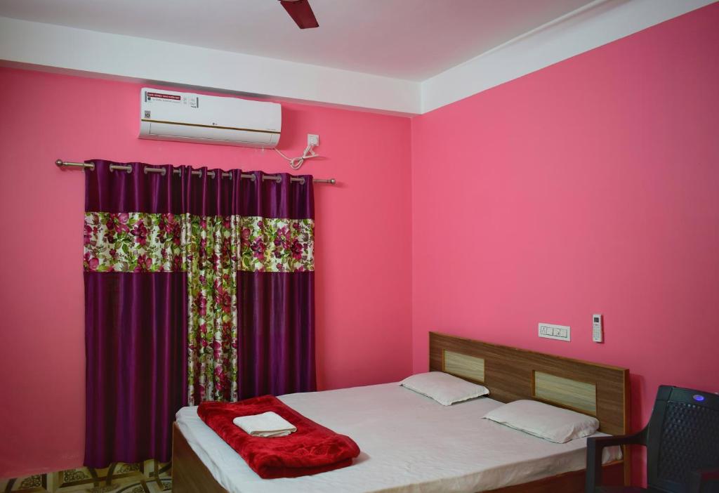 a bedroom with pink walls and a bed with a red curtain at Jupiter Lodge in Siliguri